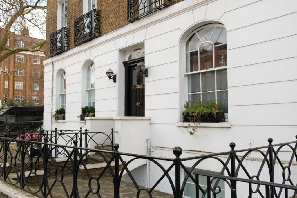 Facciata di un elegante edificio bianco con classiche finestre all'inglese a ghigliottina e inferriate decorative
