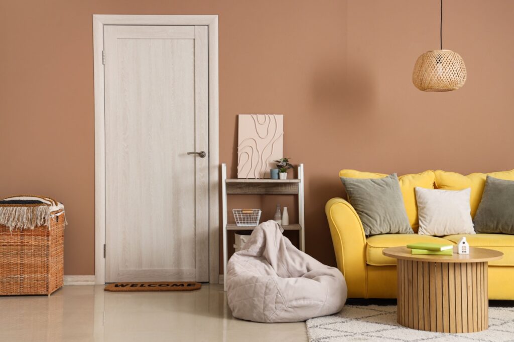 Moderna porta interna in finitura chiara all'interno di un accogliente soggiorno con divano giallo e pareti color terracotta