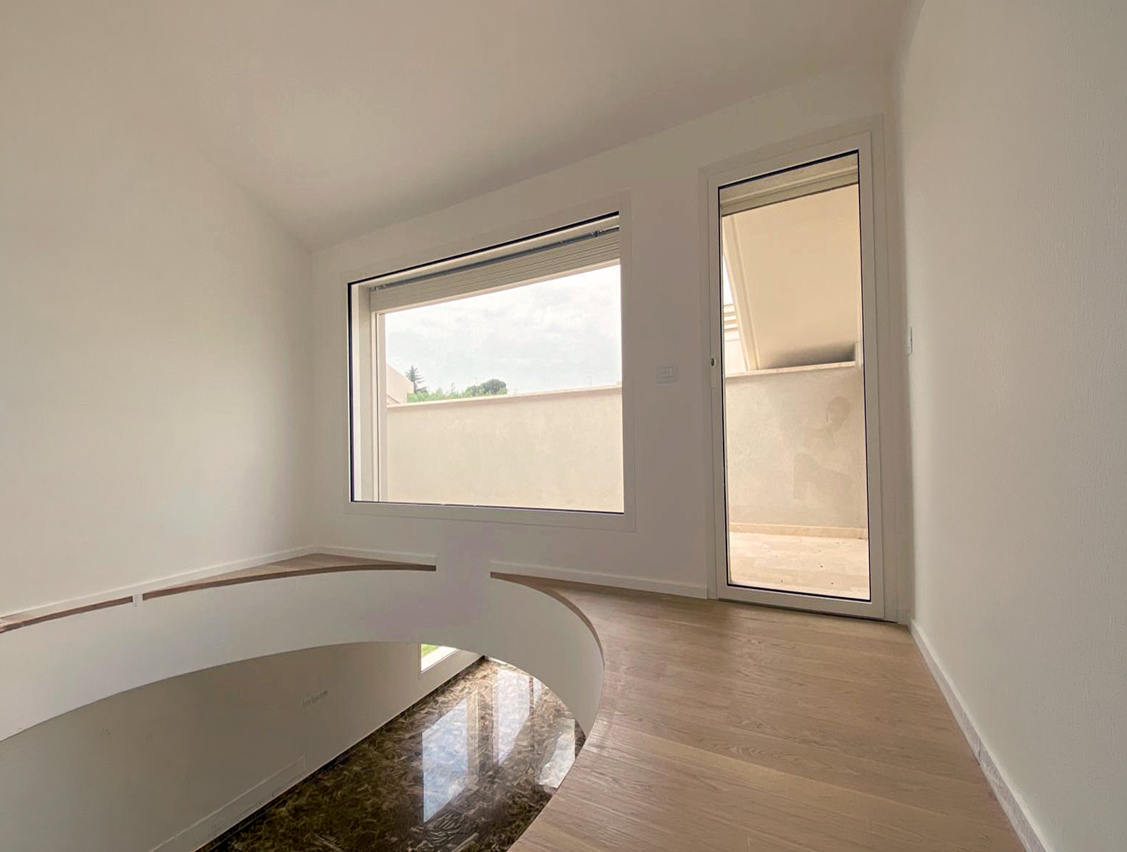 Vetrata fissa panoramica e porta finestra in alluminio Schüco affacciate su un terrazzo