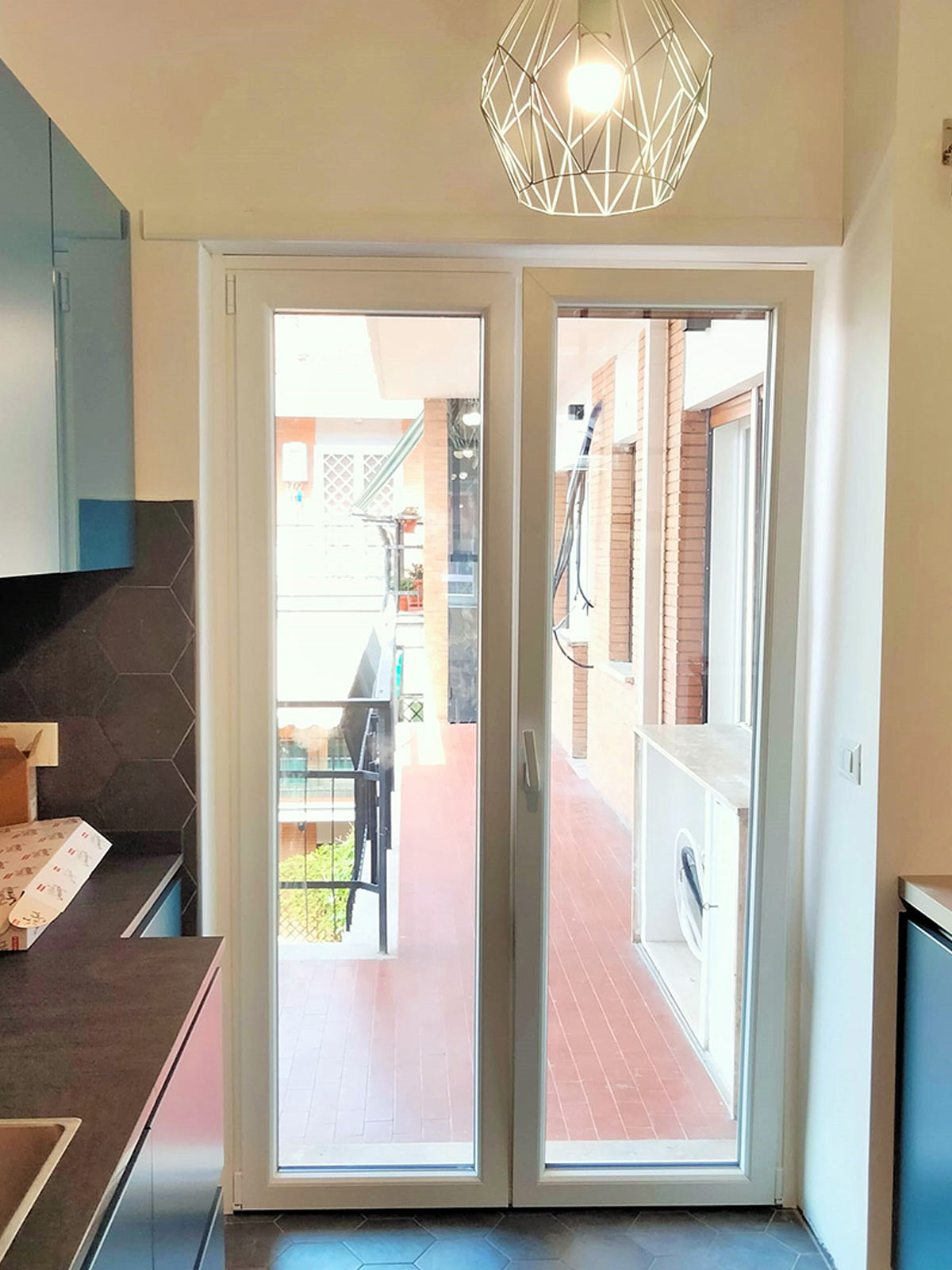 Porta finestra in PVC bianco a due ante installata in una cucina dal design moderno