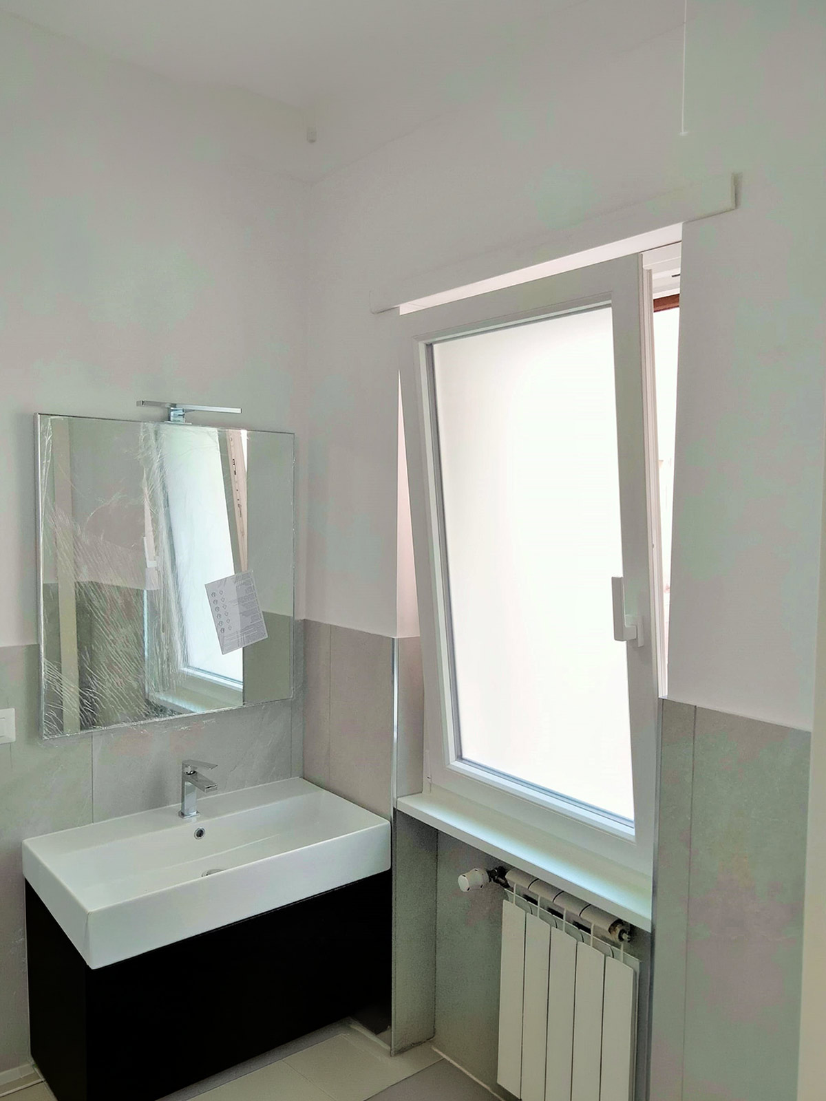 Finestra in PVC bianco in bagno con apertura ad anta a ribalta per la microventilazione