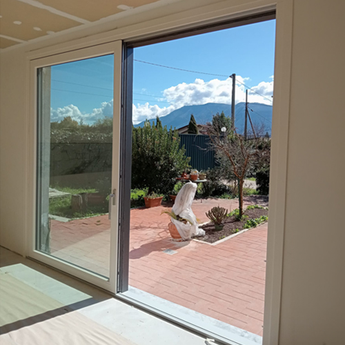 Dettaglio dell'infisso scorrevole in PVC con profilo bianco interno e grigio scuro esterno
