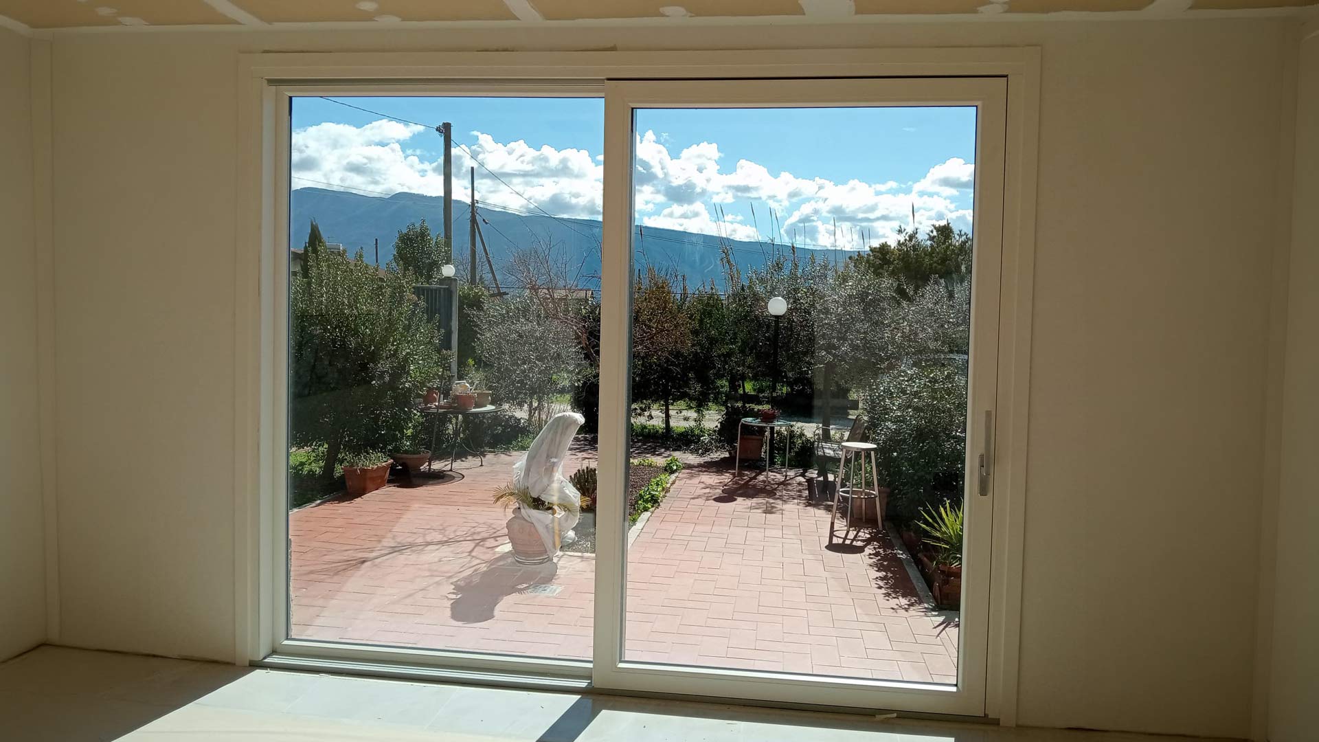 Grande infisso scorrevole in PVC bicolore aperto su un giardino ad Anagni