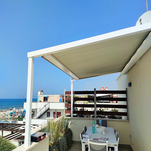 Pergola con tetto retrattile KE Hydra installata su un terrazzo vista mare a Torvaianica