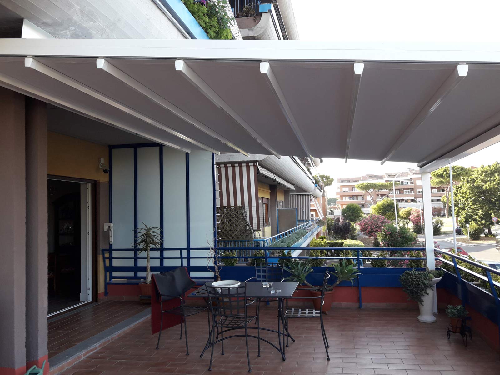 Pergotenda con struttura bianca e telo retrattile aperta su un balcone condominiale