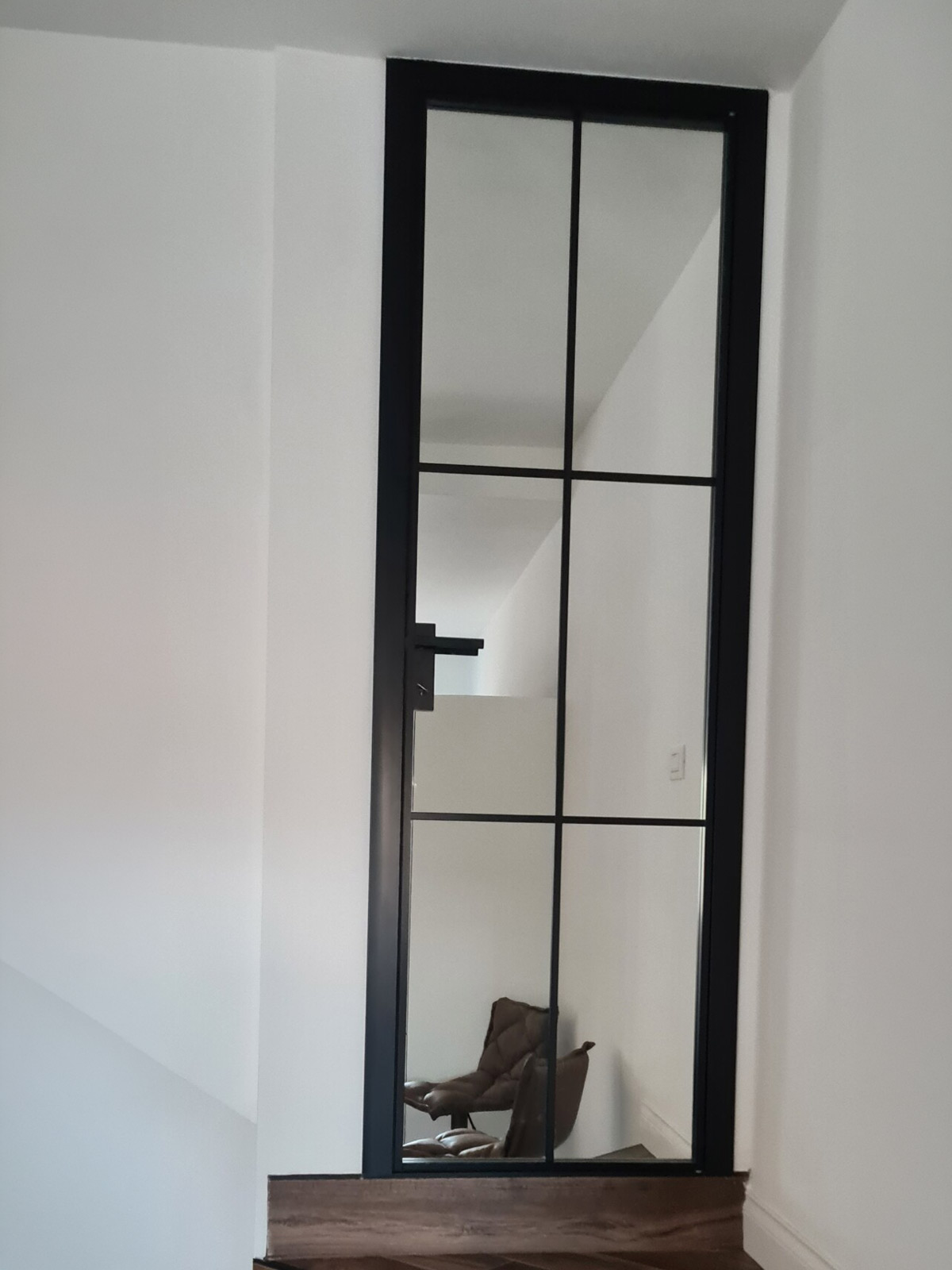 Porta interna vetrata con profilo nero installata sul pianerottolo della scala