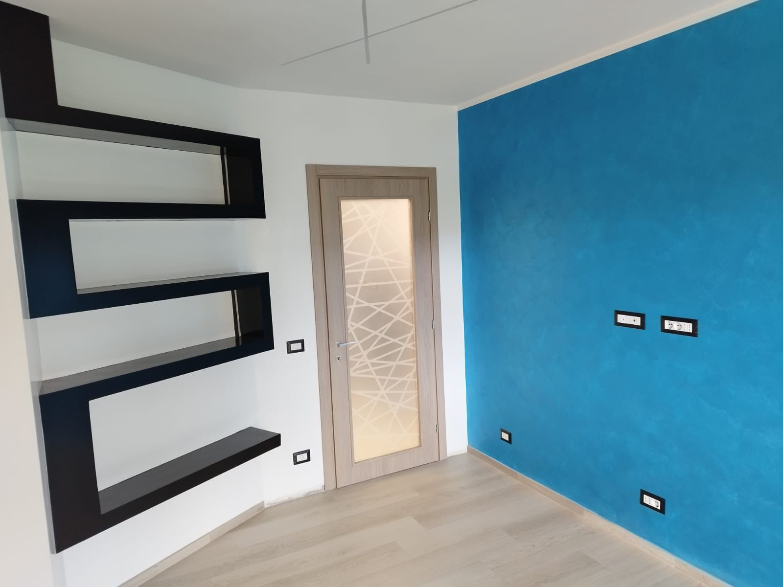 Porta interna in legno chiaro con inserto in vetro decorato in ambiente moderno
