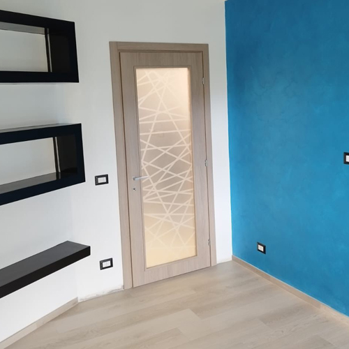 Dettaglio della porta interna in legno chiaro con pannello in vetro satinato decorato