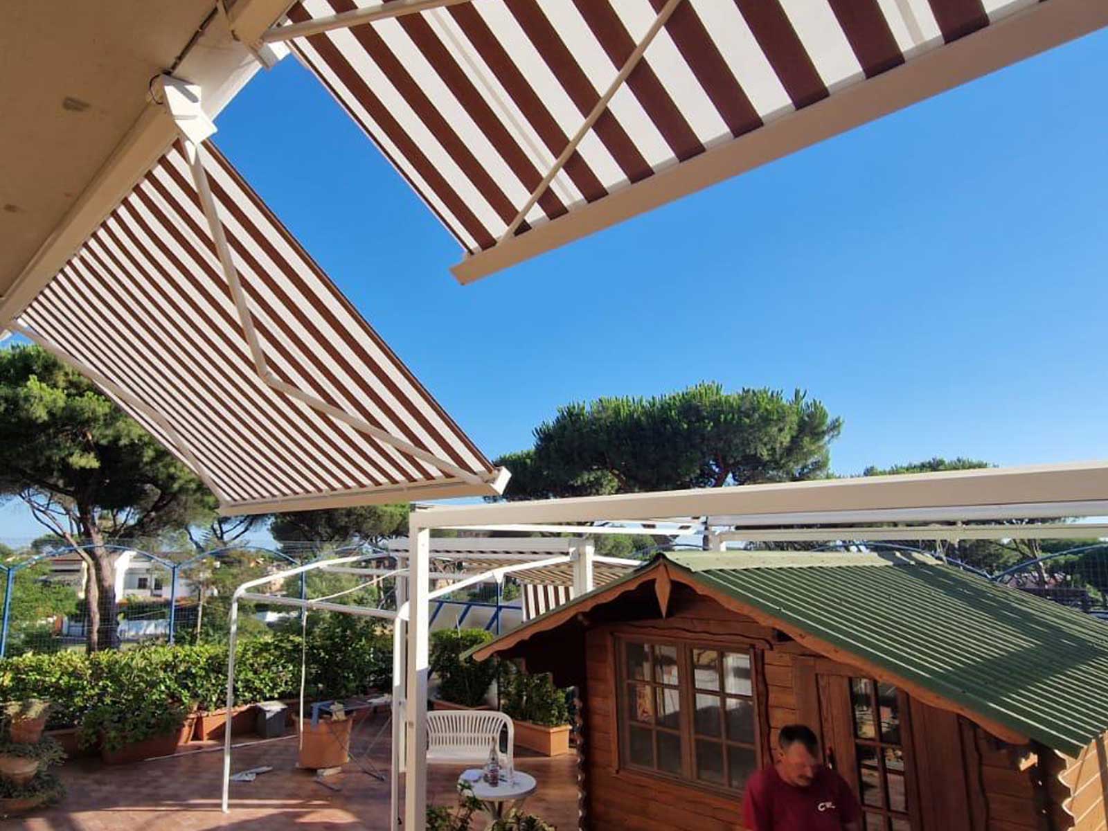 Tenda da sole a bracci estensibili con telo a righe installata su un terrazzo residenziale
