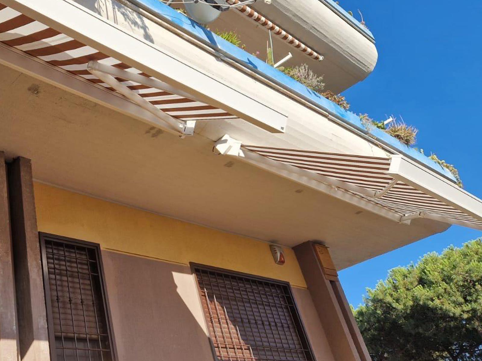 Tenda da sole a righe vista dal basso, ancorata al soffitto del balcone