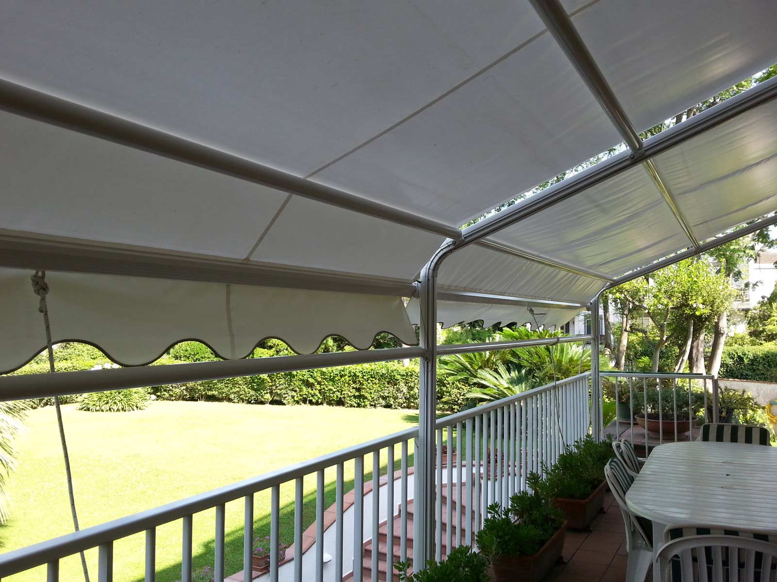 Copertura solare in tessuto bianco con mantovana a onde installata su un lungo balcone condominiale