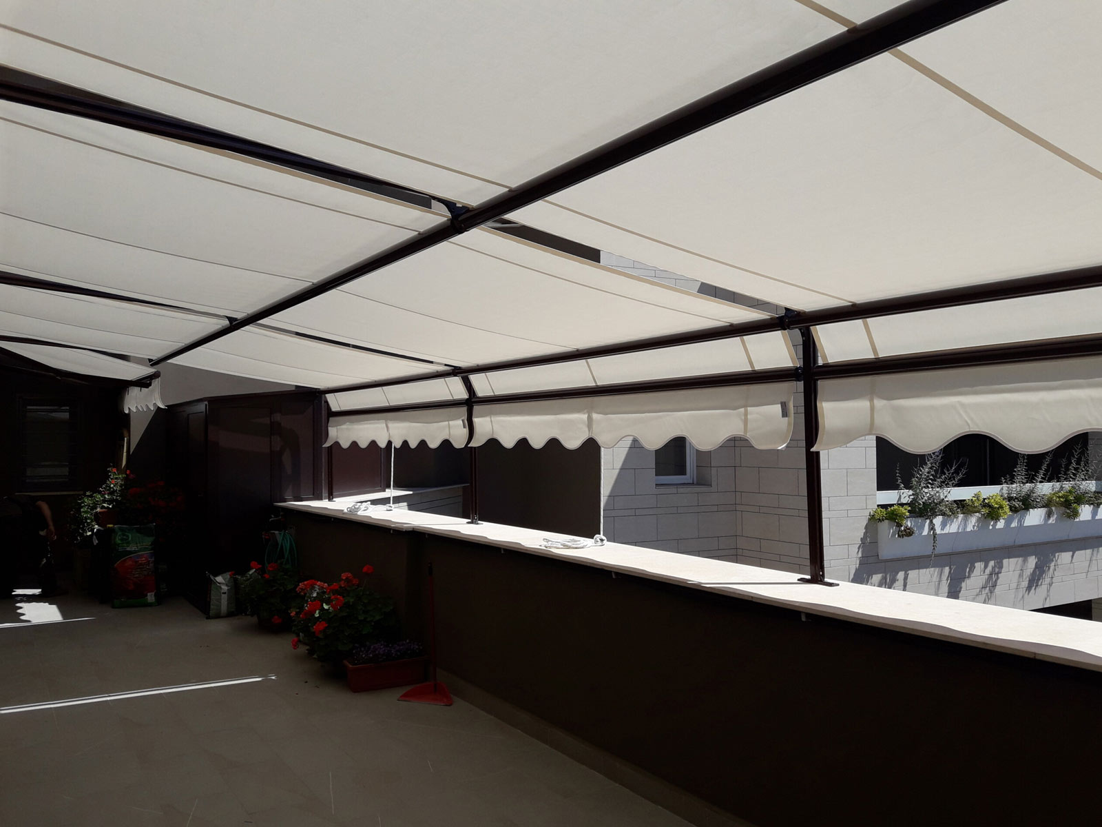Tenda scorrevole orizzontale su guide in alluminio scuro a protezione di un attico assolato