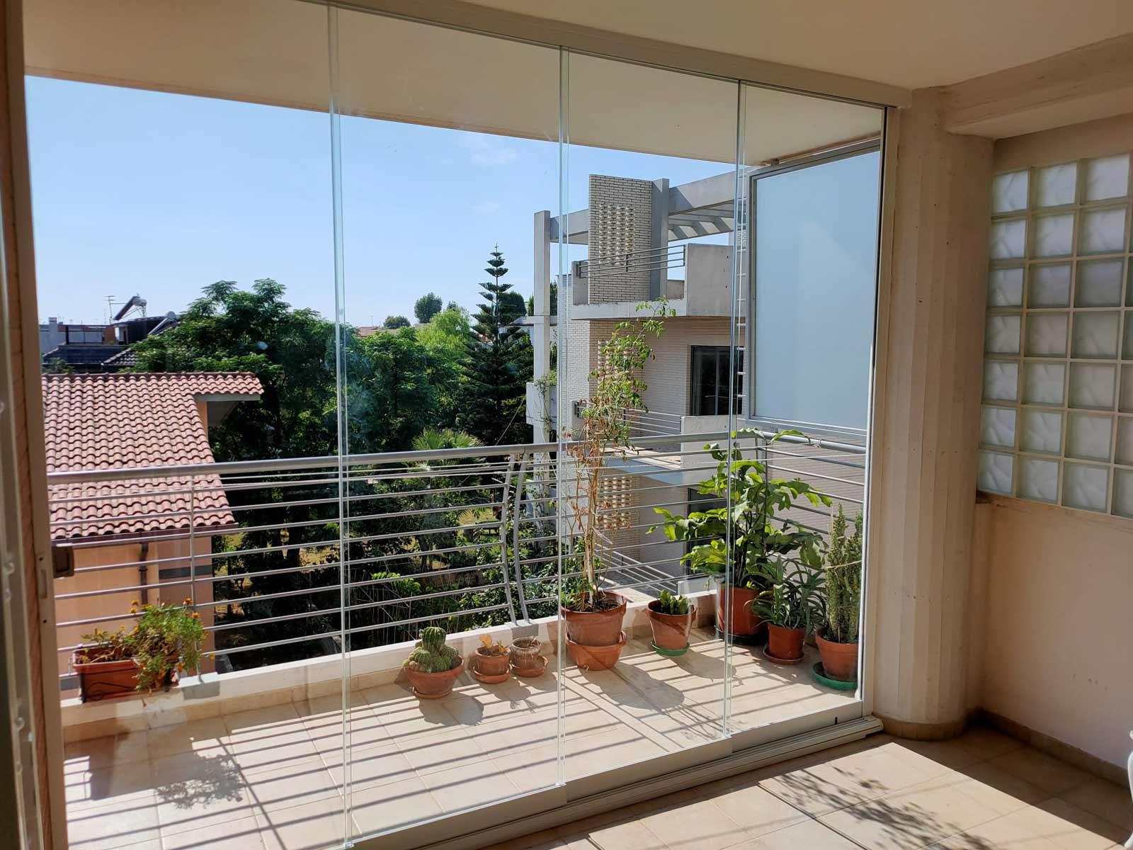 Balcone luminoso chiuso con vetrate panoramiche senza profili verticali dietro al parapetto in metallo