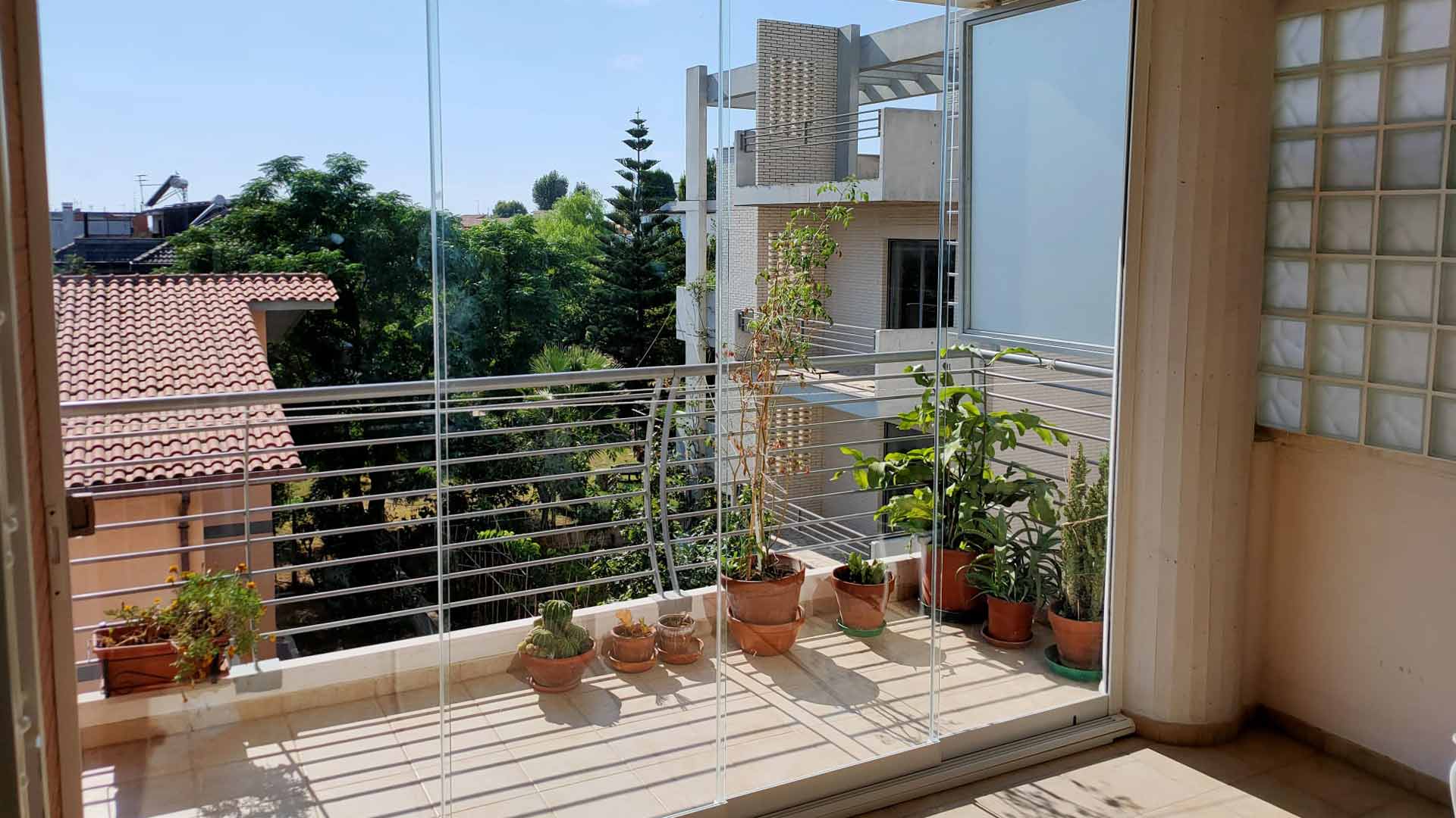 Balcone luminoso chiuso con vetrate panoramiche senza profili verticali dietro al parapetto in metallo